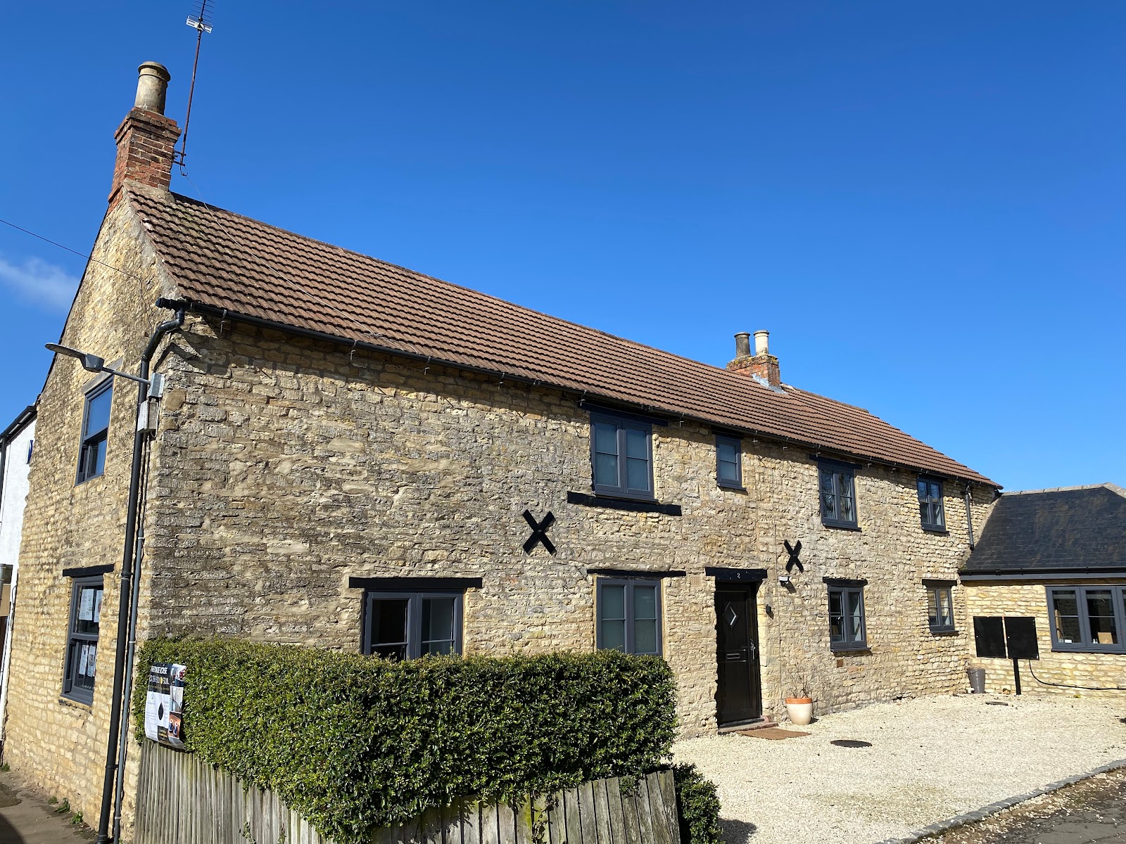The Roade House, a charming historic stone building under a clear blue sky in Roade.