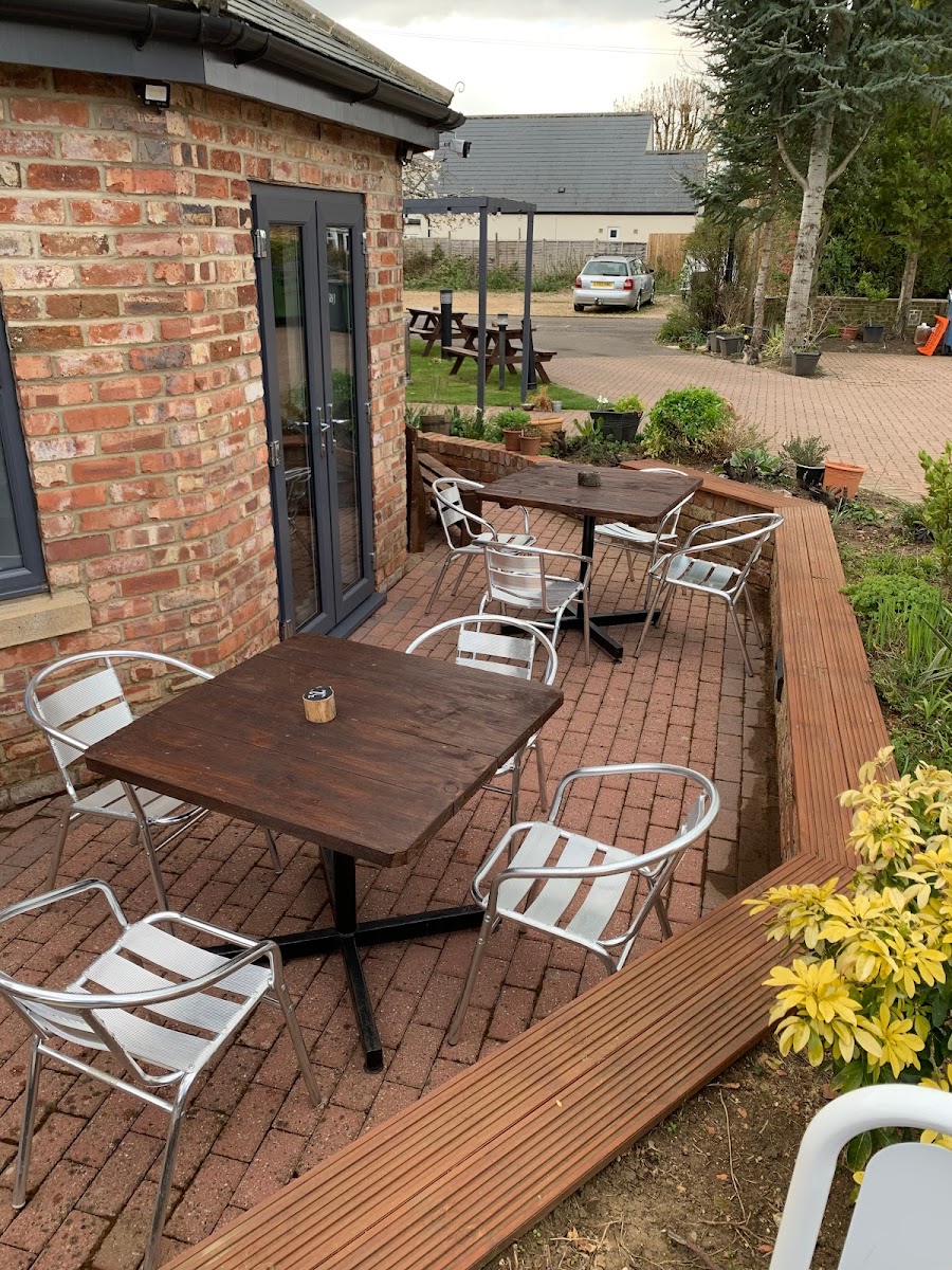 Outdoor patio seating area at The Roade House in Roade with brickwork, tables, and garden landscaping.