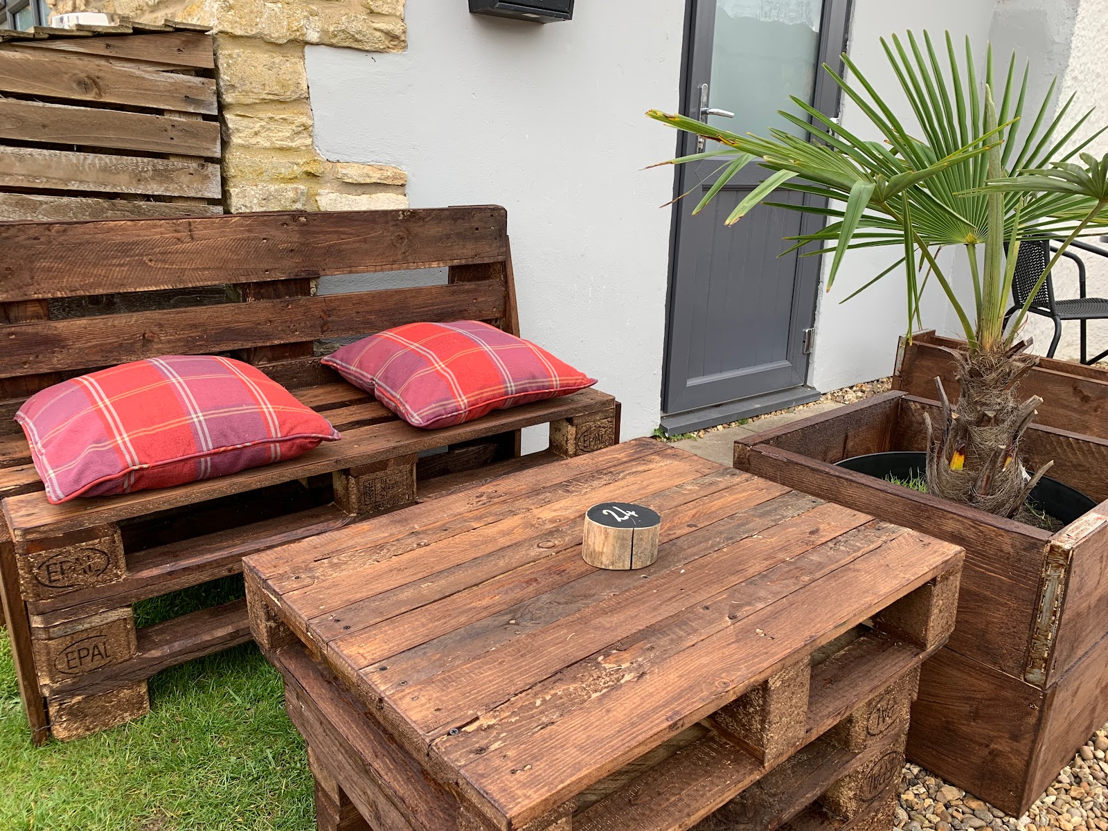Outdoor seating area with rustic pallet furniture and planters at The Roade House in Roade.